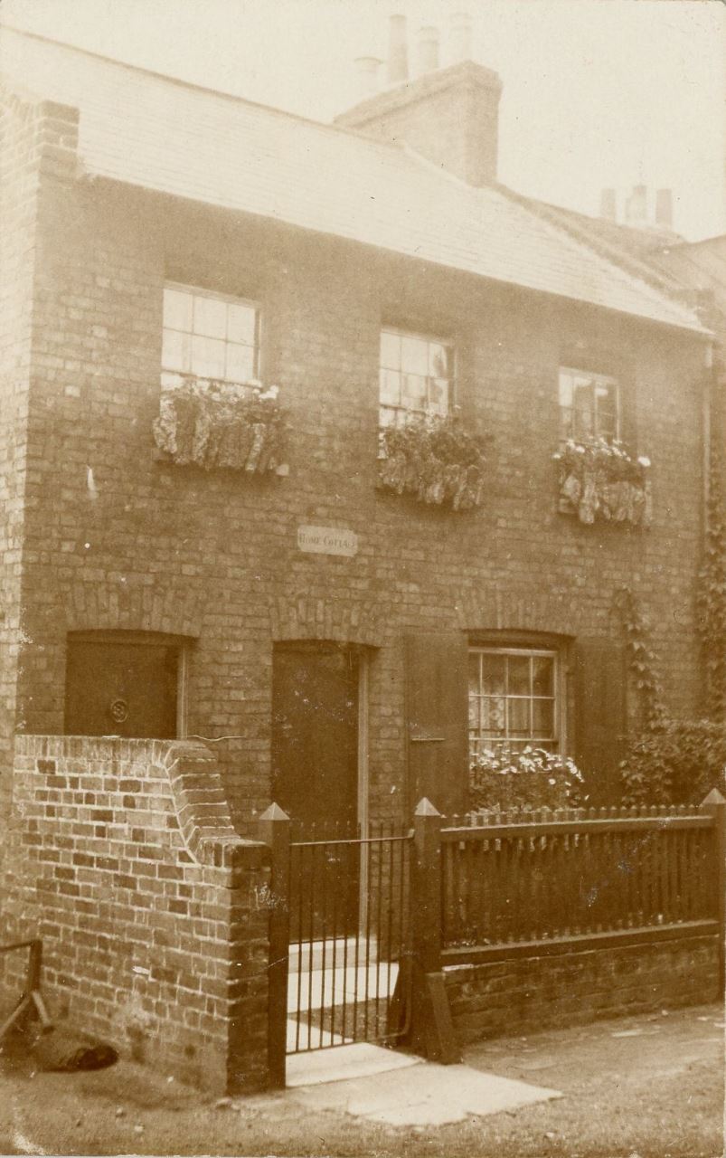 Sepia view of two-storey brick building with small, railed garden at front