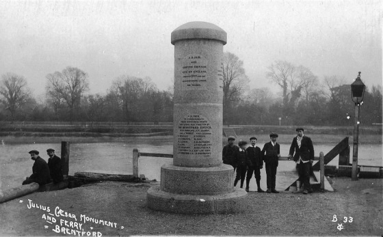Inscribed cylindrical monument about 15-20' high, river in background