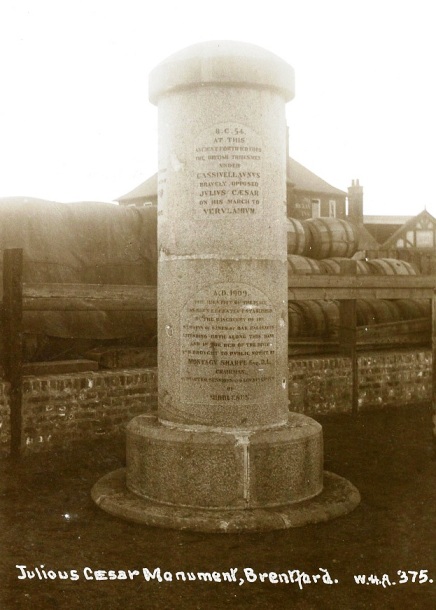 Inscribed cylindrical monument about 15-20' high, river in background