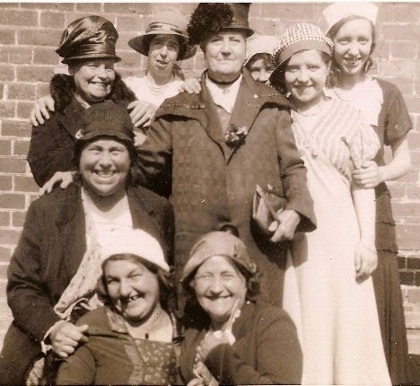 Photo taken outside, nine ladies dressed up, all smiles, all in hats, seven aged 40+ and two younger