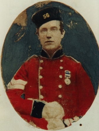 Oval portrait photo, hand coloured, of soldier, red uniform, medal