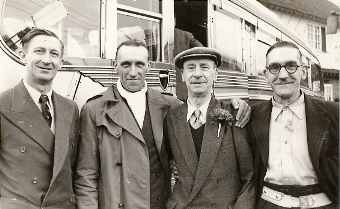 Photo of four men with coach behind