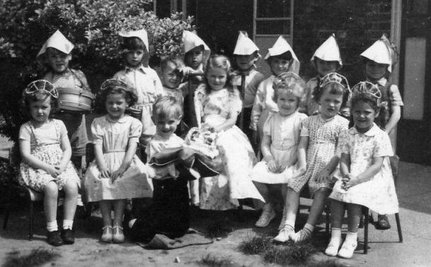Small children, boys wearing pointy paper hats, girls wearing small tiaras